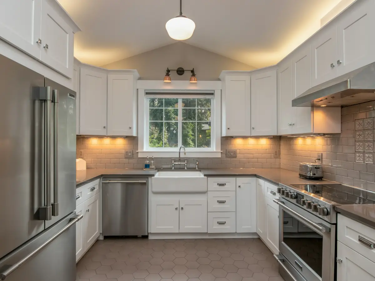 After: a kitchen with white cabinets and hidden lighting