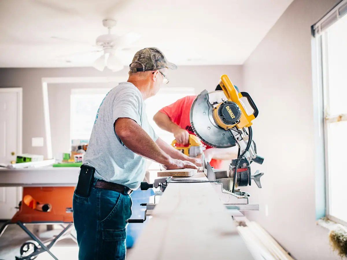 Two craftsmen cutting timber with a mitre saw