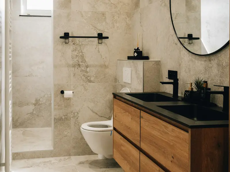 A bathroom with marble-look tiles and a wooden vanity