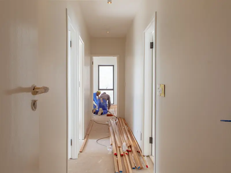A craftsman laying flooring in a hallway